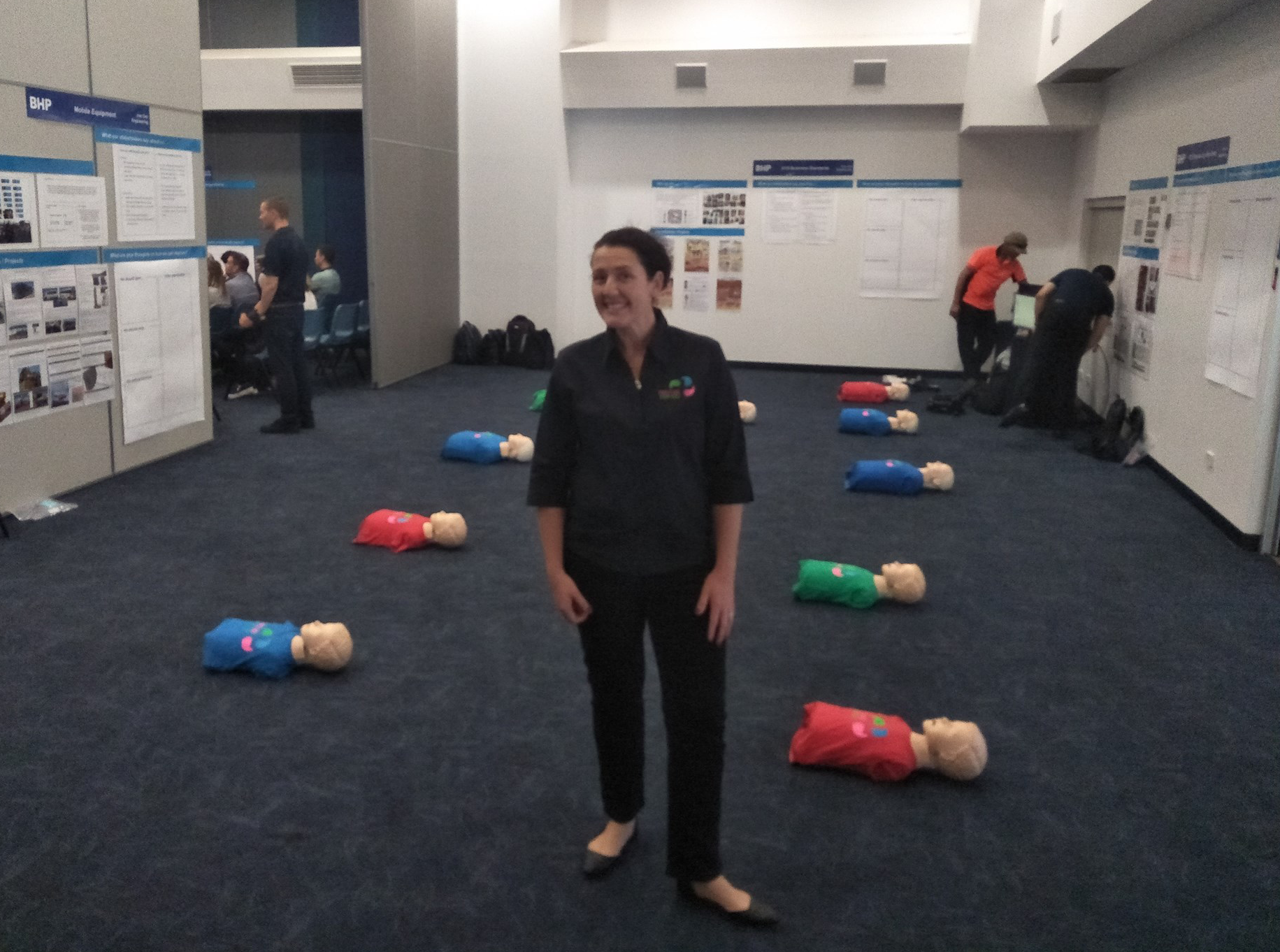 Image of Mary Dawes ready to train CPR with two rows of mannequins